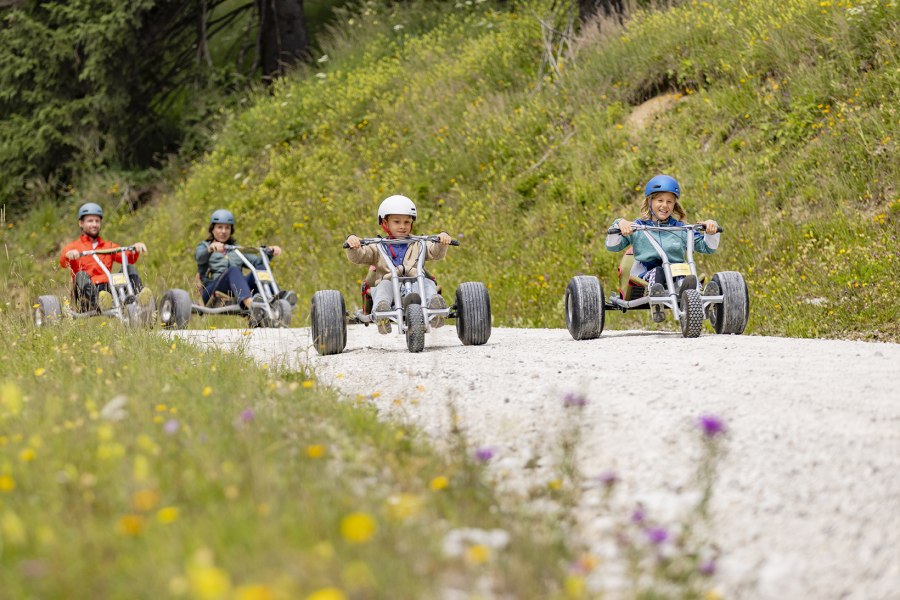 Familie fährt mit den Mountaincarts ins Tal