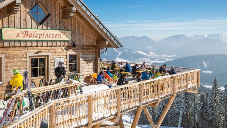 Hütte s'Balzplatzerl mit Gästen die auf der Sonnenterrasse sitzen